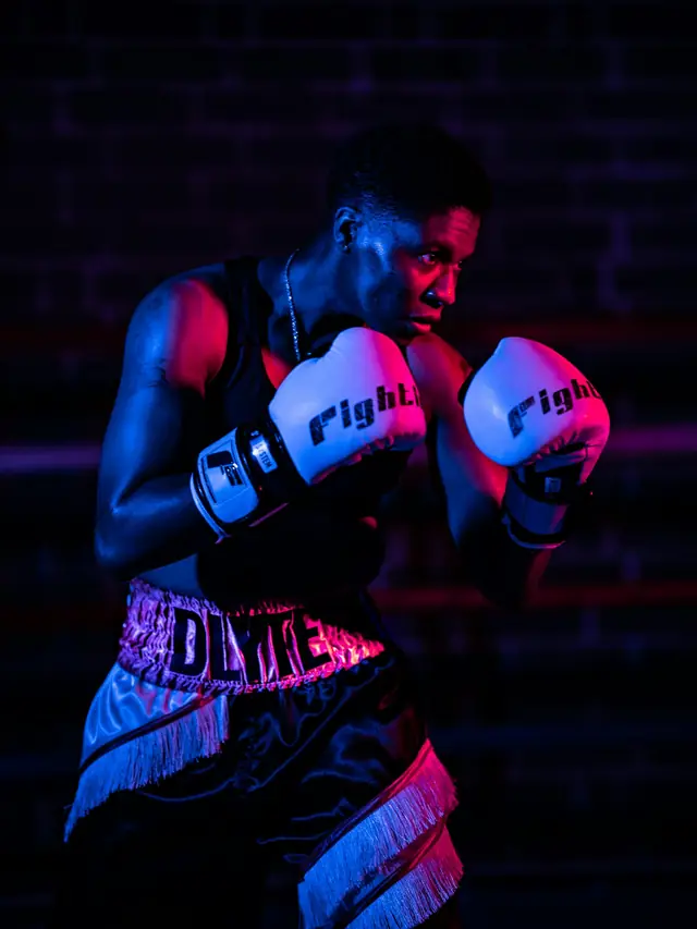 Boxeador con guantes en guardia iluminado con luces rojas y azules
