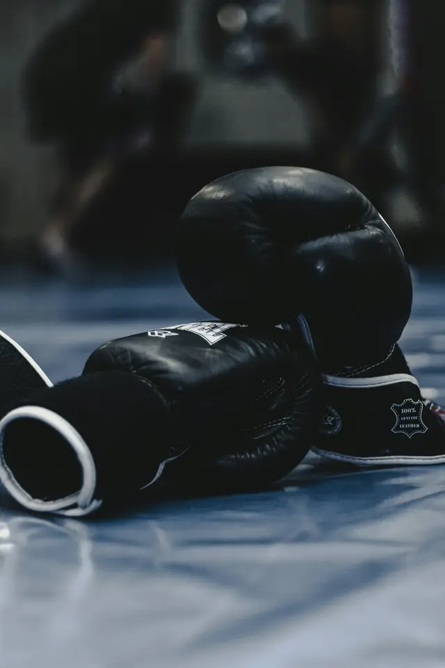Par de guantes de boxeo negros en el suelo, en penumbra